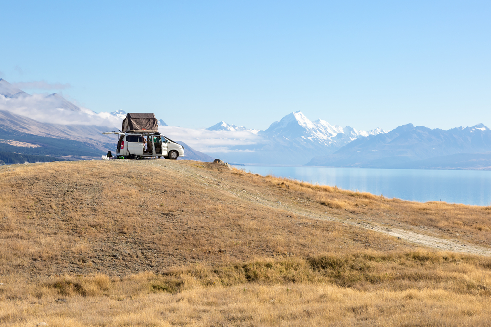 A camping van with a tent in front of lake