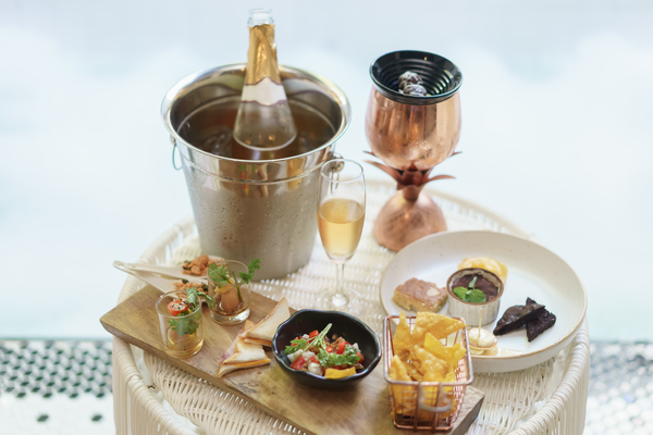 A glass of wine and wine bottle with different snacks and appetiser