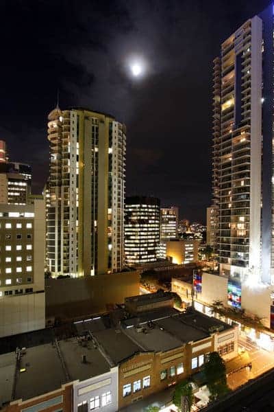 A moonlit view of Brisbane's cityscape at night, showcasing the contrast between the bustling urban life and serene sky — a perspective that reflects the ongoing comparison of lifestyle and attractions in Brisbane vs. Adelaide.