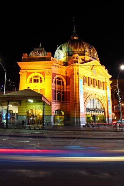 Flinders Street Station in Melbourne illuminated at night, showcasing its historic architecture and bustling atmosphere. This image complements the discussion about Melbourne's rich cultural heritage and the origin of its name in the blog post.