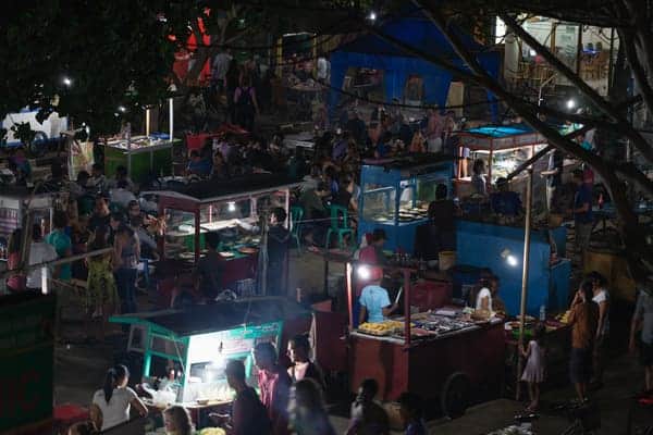 Bustling night market on the Gili Islands with various food stalls and a crowd of people, showcasing the vibrant local cuisine as a popular activity among things to do in Gili Islands.
