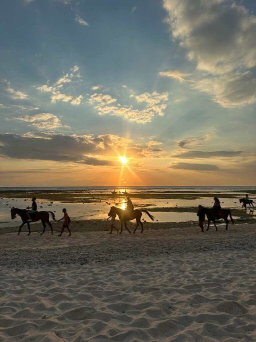 Golden sunset on a Gili Island beach with silhouettes of people horseback riding along the shore, an idyllic scene that epitomises the tranquil experiences to be had while exploring things to do in Gili Islands.