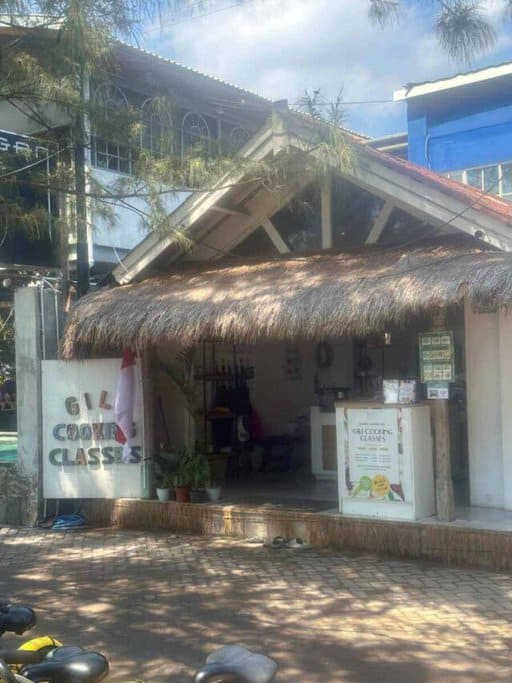 Exterior view of Gili Cooking Classes, a thatched-roof establishment offering culinary lessons on the Gili Islands. Participating in a cooking class is a flavourful addition to Gili Islands activities for those looking to learn local recipes and cooking techniques.