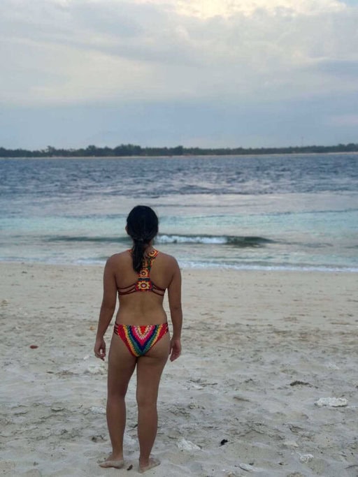 Me in a colourful bikini stands on the sandy shores of the Gili Islands, gazing out at the tranquil sea, epitomising the relaxed beach atmosphere of Gili Meno Beach. Enjoying the pristine beaches is one of the quintessential Gili Islands attractions and activities for visitors.