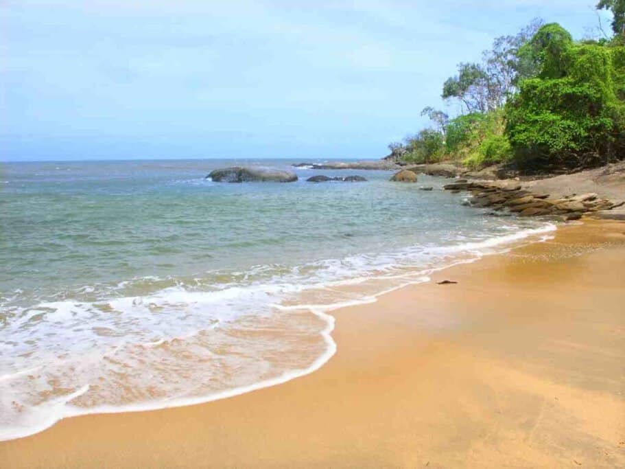 A tranquil beach scene with gentle waves kissing the golden sands of Trinity Beach in Cairns, inviting visitors to enjoy peaceful beach walks as a winter activity.