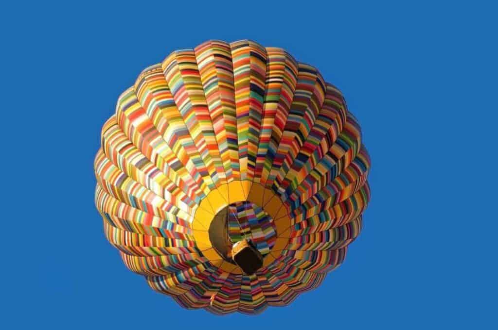 A vibrant hot-air balloon soaring in the clear blue sky, offering a unique perspective on the landscapes and is one of the most popular things to do in Cairns in winter.