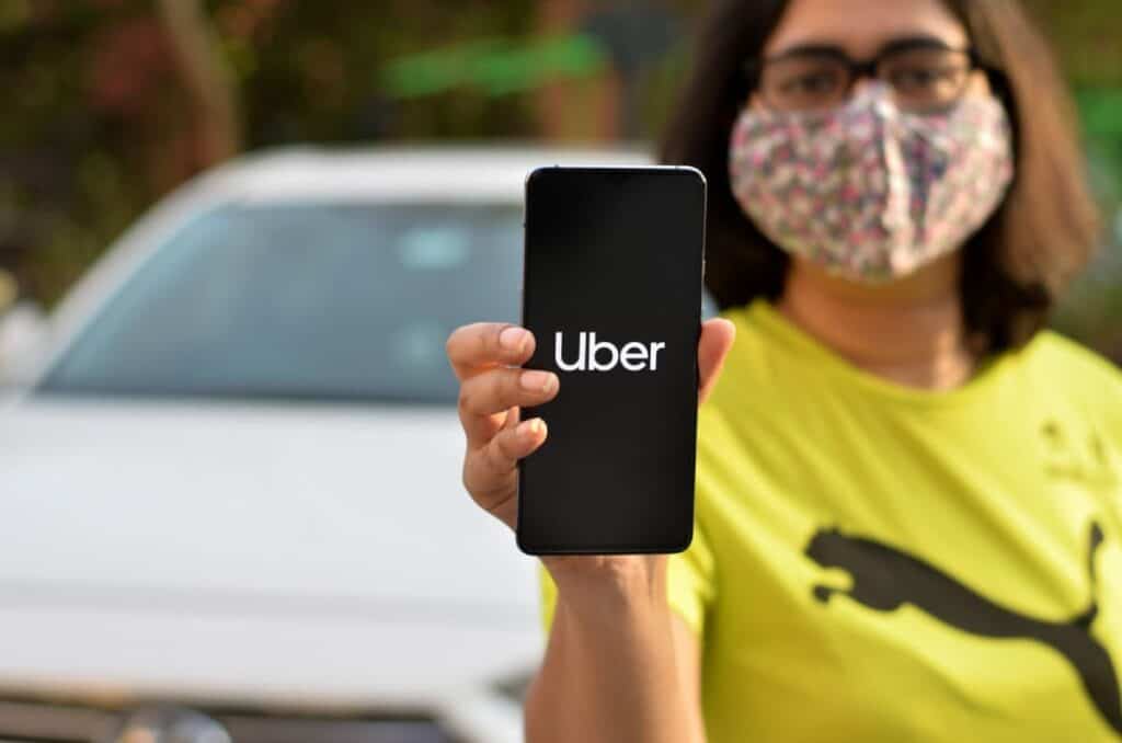 Person holding a mobile phone displaying the Uber app, symbolizing Uber's availability in Melbourne.