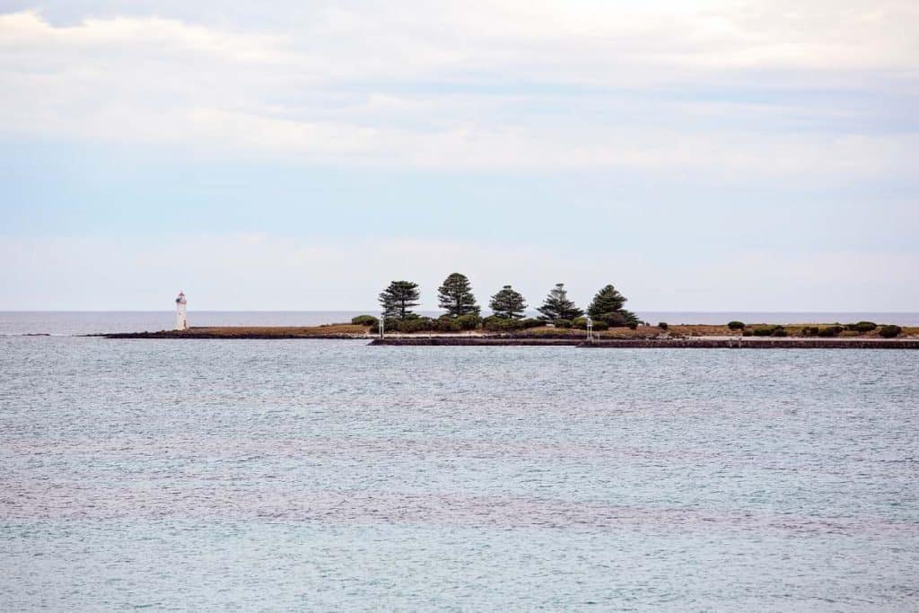 A lighthouse on the rocky point of Port Fairy, Australia, surrounded by calm ocean waters. This peaceful coastal setting reflects the charm of the town and provides inspiration for travellers deciding where to stay in Port Fairy.