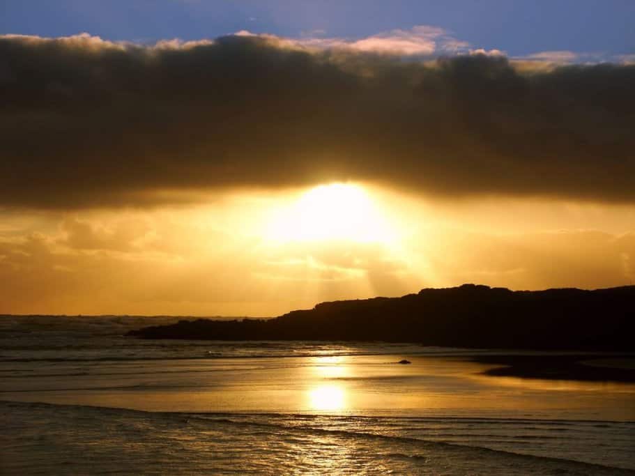 A stunning sunset over the beach in Warrnambool, Australia, with golden light reflecting on the water. This serene view highlights the beauty of the area and is a perfect backdrop for exploring where to stay in Warrnambool.