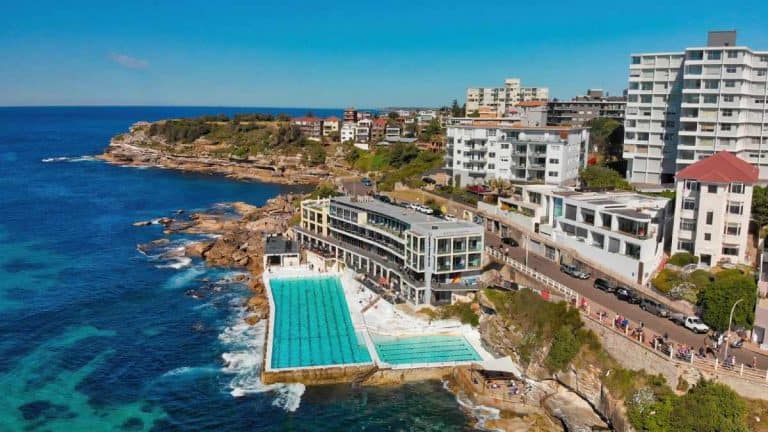 Aerial view of Bondi Beach's iconic coastal pool and surrounding neighbourhood in Sydney, showcasing the vibrant oceanfront. This image highlights the beauty of Bondi Beach and helps answer the question of when to visit Bondi Beach for stunning views and experiences.