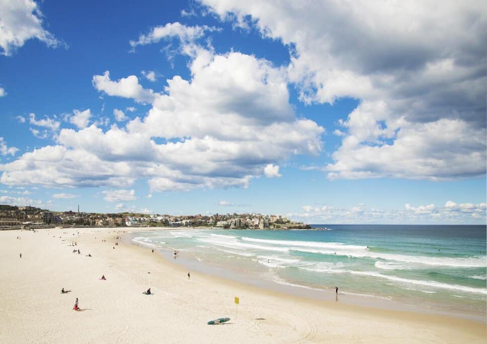 A wide view of Bondi Beach's sandy shoreline and turquoise waves under a partly cloudy sky. This serene scene captures the charm of Bondi Beach and offers insights into the best time to visit Bondi Beach for a relaxing experience."