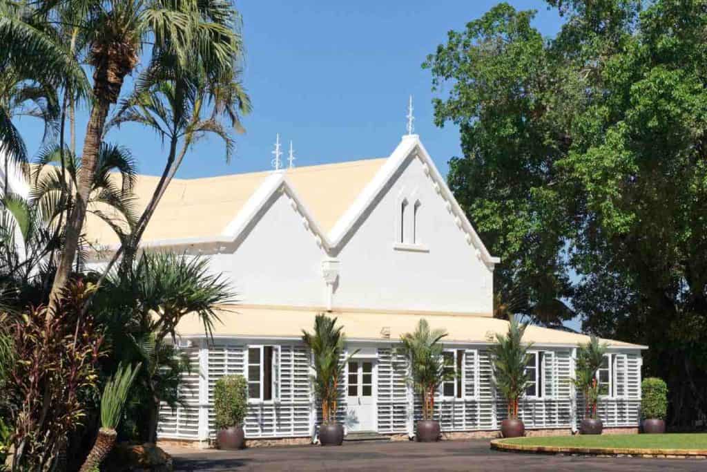 Historic Government House in Darwin surrounded by tropical greenery and bright skies. This image highlights the city’s blend of history and tropical charm, which plays into the lifestyle factors people weigh when looking at the advantages and disadvantages of living in Darwin.