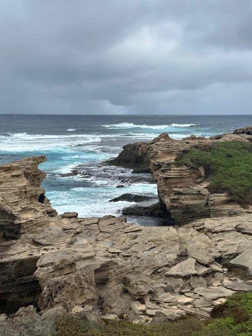 Dramatic coastal cliffs and crashing waves at Cape Vlamingh on Rottnest Island under a moody sky – a breathtaking natural stop often featured at the end of a scenic Rottnest Island itinerary for its raw beauty and remote vibe.