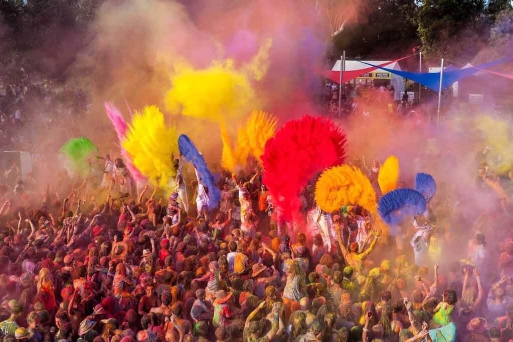 Crowd celebrating with bright clouds of coloured powder rising into the air at a lively outdoor event, capturing the fun and cultural energy that makes gatherings like this some of the top music festivals in Australia featured in the blog post.