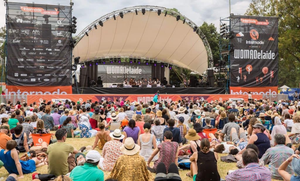Large crowd sitting on the grass watching a live performance on the WOMADelaide main stage in Adelaide’s Botanic Park, highlighting the relaxed outdoor vibe that makes events like this some of Australia’s best music festivals featured in the blog post.