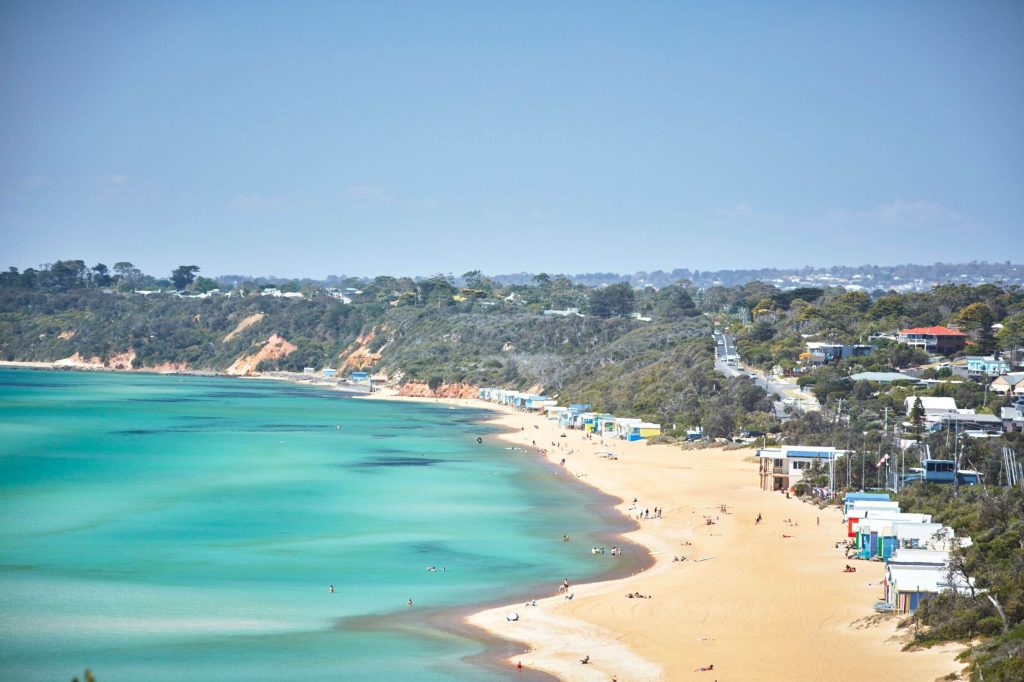 Turquoise water meeting golden sand at Mount Martha Beach with colourful bathing boxes lining the shore, showcasing one of the best beaches in Australia featured in the Australia’s Best Beaches guide.