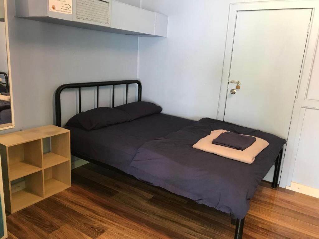Simple private room at a backpackers hostel in Alice Springs with a double bed, timber floors, and basic shelving, ideal for travellers searching for cheap places to stay in Alice Springs on a budget.