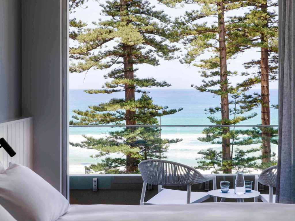 Hotel balcony with ocean view through Norfolk pine trees at Manly Pacific Sydney MGallery Collection, highlighting Manly Sydney accommodation with beachfront views in one of the best suburbs to stay in Sydney