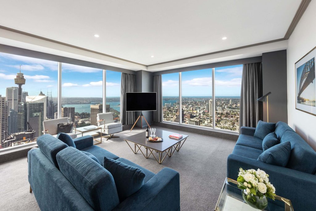 A high-rise suite at Meriton Suites World Tower in the Sydney CBD, featuring floor-to-ceiling windows with panoramic Sydney harbour and city skyline views, one of the best hotels in Sydney city centre for couples seeking apartment-style luxury.