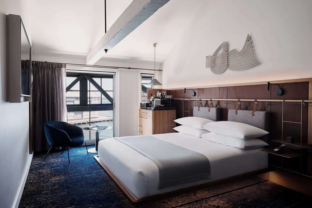 A stylish king room at Pier One Sydney Harbour Marriott Autograph Collection in The Rocks, featuring industrial-chic warehouse design, waterfront views over Walsh Bay, and one of the best Sydney harbour views hotels for couples.