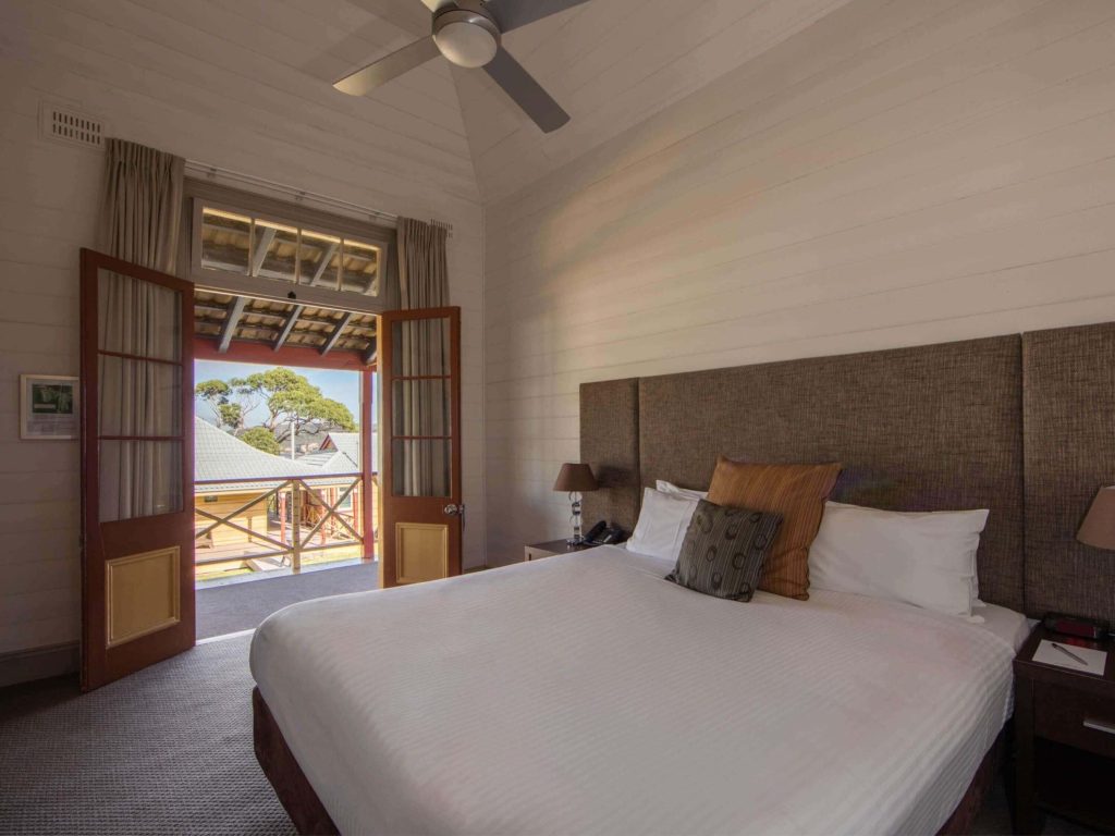 Historic-style hotel room with open balcony doors at Q Station in Manly, highlighting peaceful Manly Sydney accommodation in one of the best areas to stay in Sydney for harbour views and nature escapes