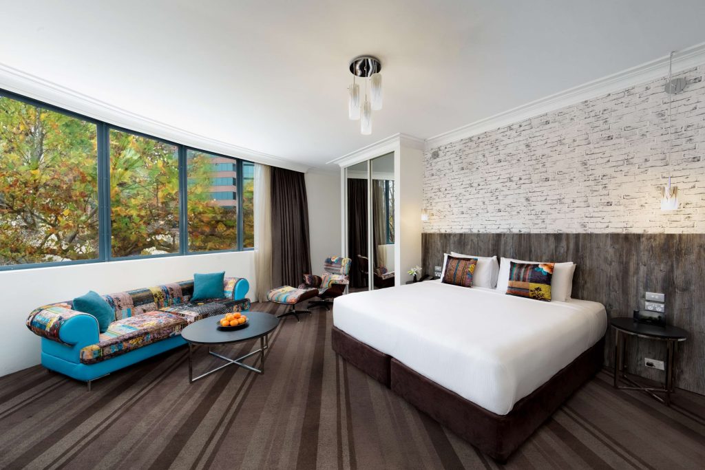 Spacious modern hotel room with lounge seating and large windows in Surry Hills Sydney, highlighting comfortable Sydney accommodation in one of the best areas to stay in Sydney with easy public transport Sydney access