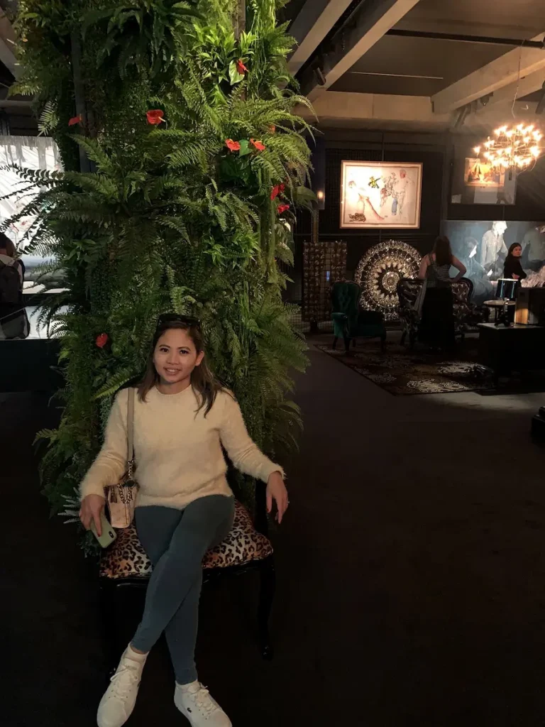 A person seated on a patterned chair inside the Museum of Old and New Art in Hobart, surrounded by lush greenery, contemporary artwork, and dramatic ambient lighting. A unique cultural experience on a Tasmania travel itinerary, MONA blends immersive art installations, striking interiors, and thought provoking exhibits in one of Australia's most distinctive museums.