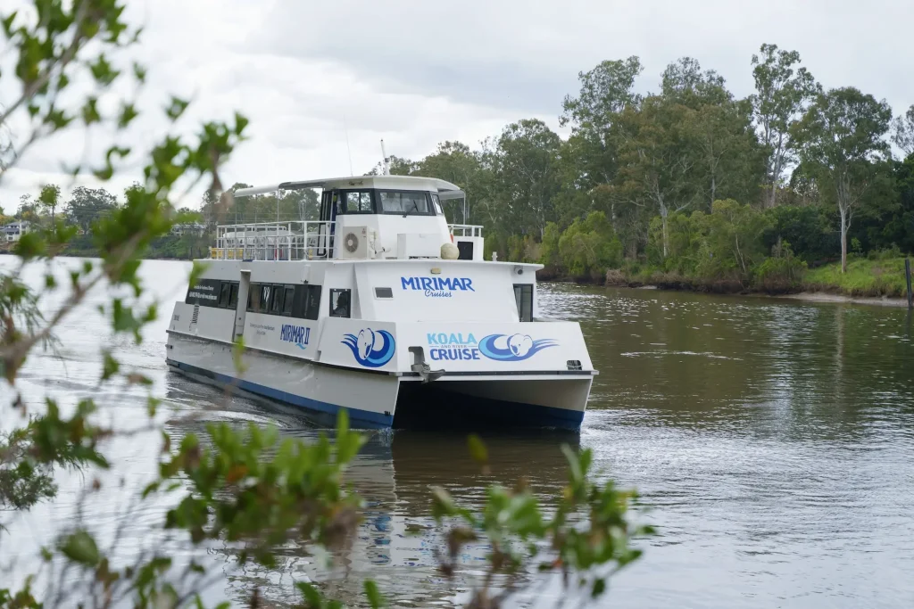 Mirimar Cruises "KOALA AND RIVER CRUISE" boat travelling along the Brisbane River surrounded by leafy riverbanks. Taking a river cruise is a scenic way to explore Brisbane and visit the citys wildlife attractions.