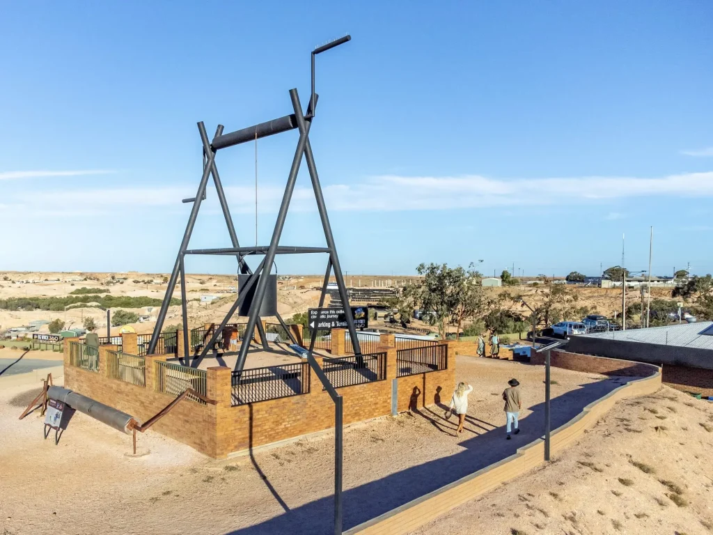 Giant black mining winch structure towering over the dusty desert landscape at the Big Winch Complex. Visiting this landmark is one of the classic things to do in Coober Pedy.