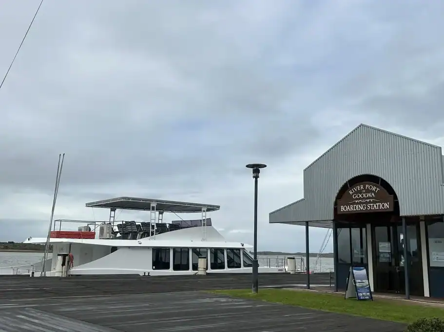 Cruise boat moored at the River Port of Goolwa Boarding Station on the Murray River beneath an overcast sky. A river cruise from Goolwa is a relaxing way to experience the Fleurieu Peninsula's waterways and historic river port.