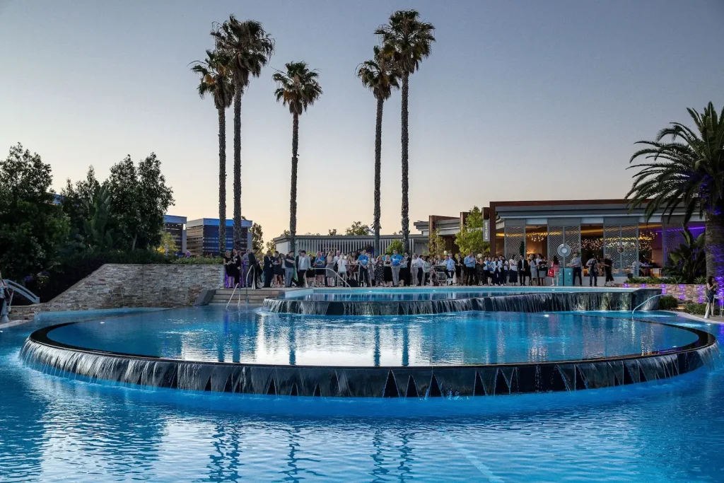 The tiered lagoon-style Crown Pools with cascading waterfalls and tall palm trees at dusk, part of Crown Towers, one of the top Perth hotels with a pool