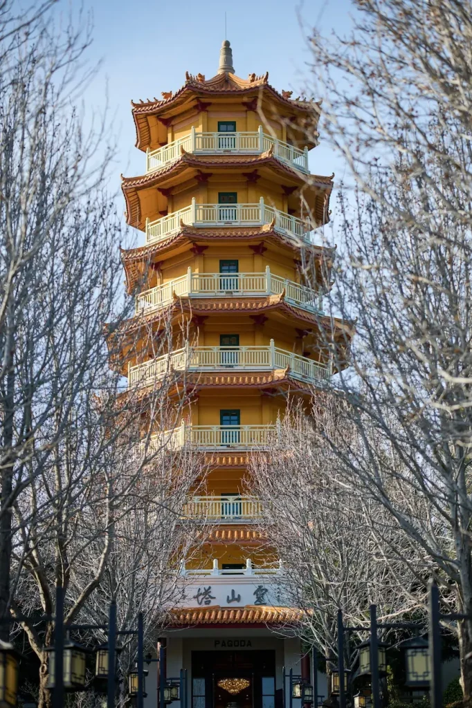 Tall golden pagoda at Nan Tien Temple in Berkeley framed by bare tree branches against a clear blue sky. The Buddhist temple is a nearby stop to combine with a trip to Sea Cliff Bridge Lookout.