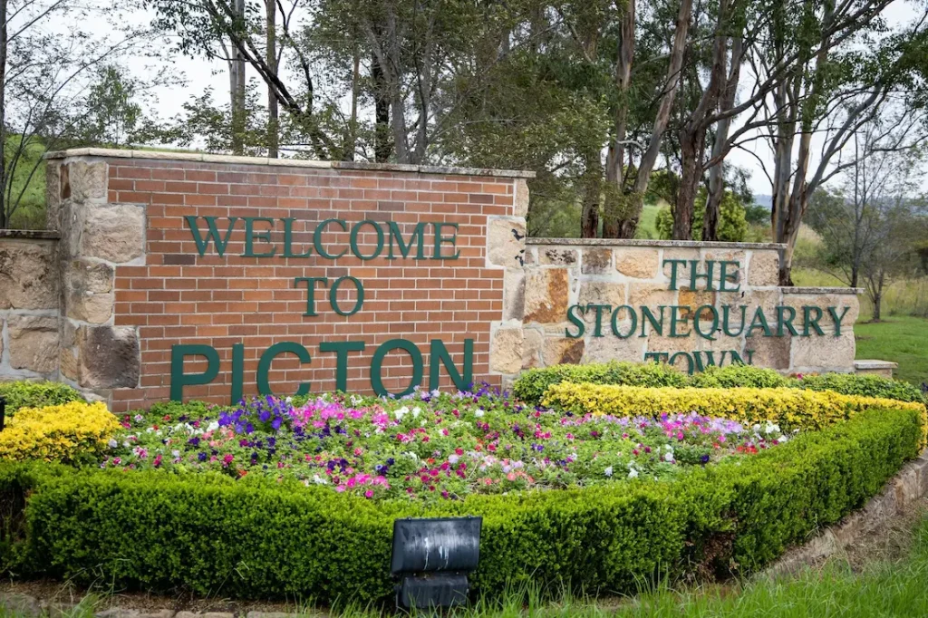 Bright petunias in front of the Picton welcome sign, a town known as one of the most haunted places near Sydney